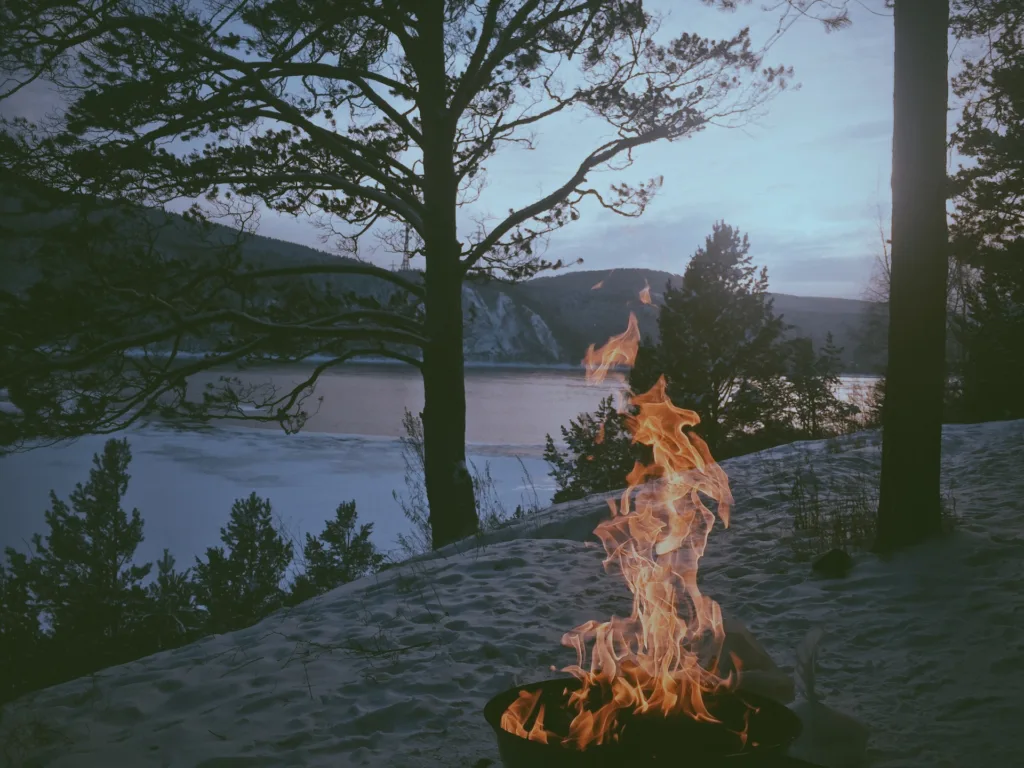 Well lit fire in a snow covered camping spot.